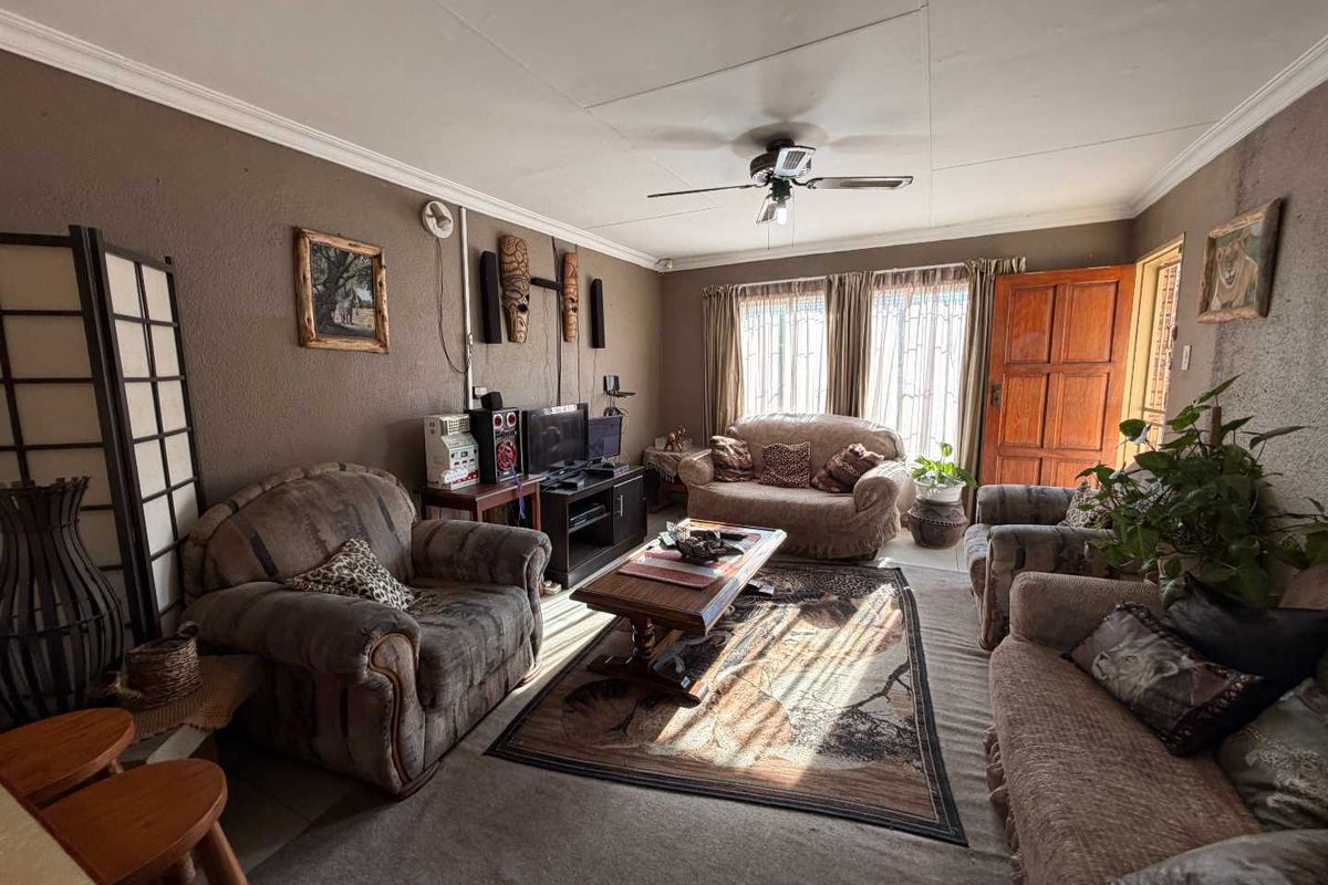 A cozy living room featuring tiled flooring, a ceiling fan, and crown molding, with natural light entering through the window and door.