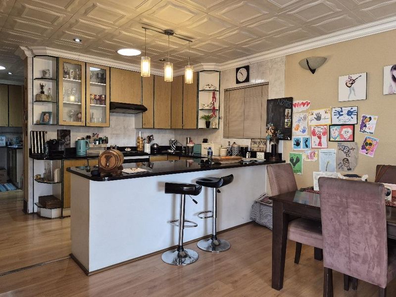 Open-plan kitchen and dining area featuring wood-finish cabinetry, granite countertops, a breakfast bar, and a distinctive coffered ceiling.
