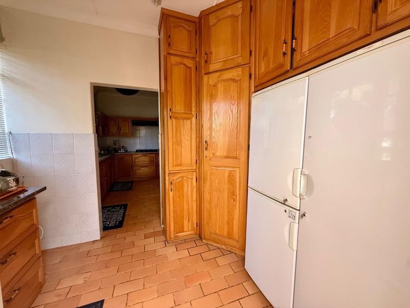 A functional kitchen featuring traditional wooden cabinetry, tiled flooring, and a tiled splashback, offering a classic layout with potential for modern updates.