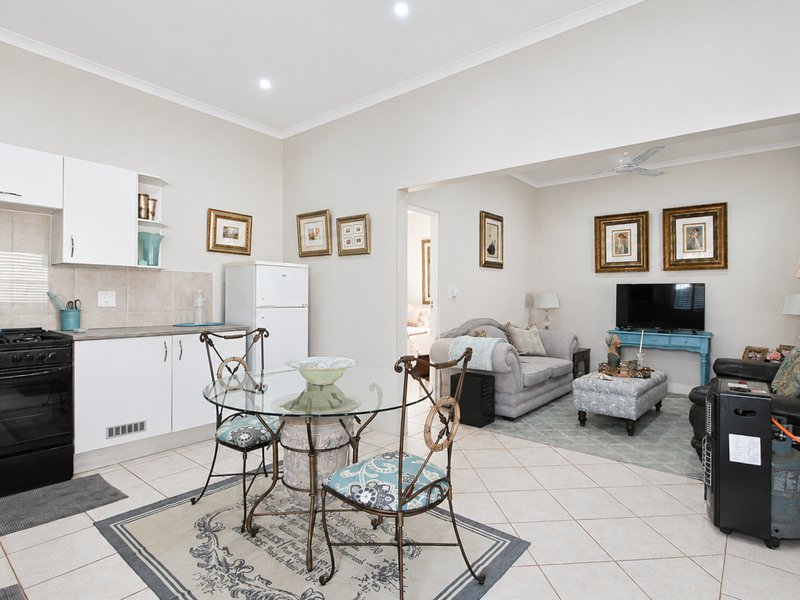 Open-plan living and kitchen area featuring tiled flooring, built-in cabinetry, and a gas stove, creating a functional and connected living space.