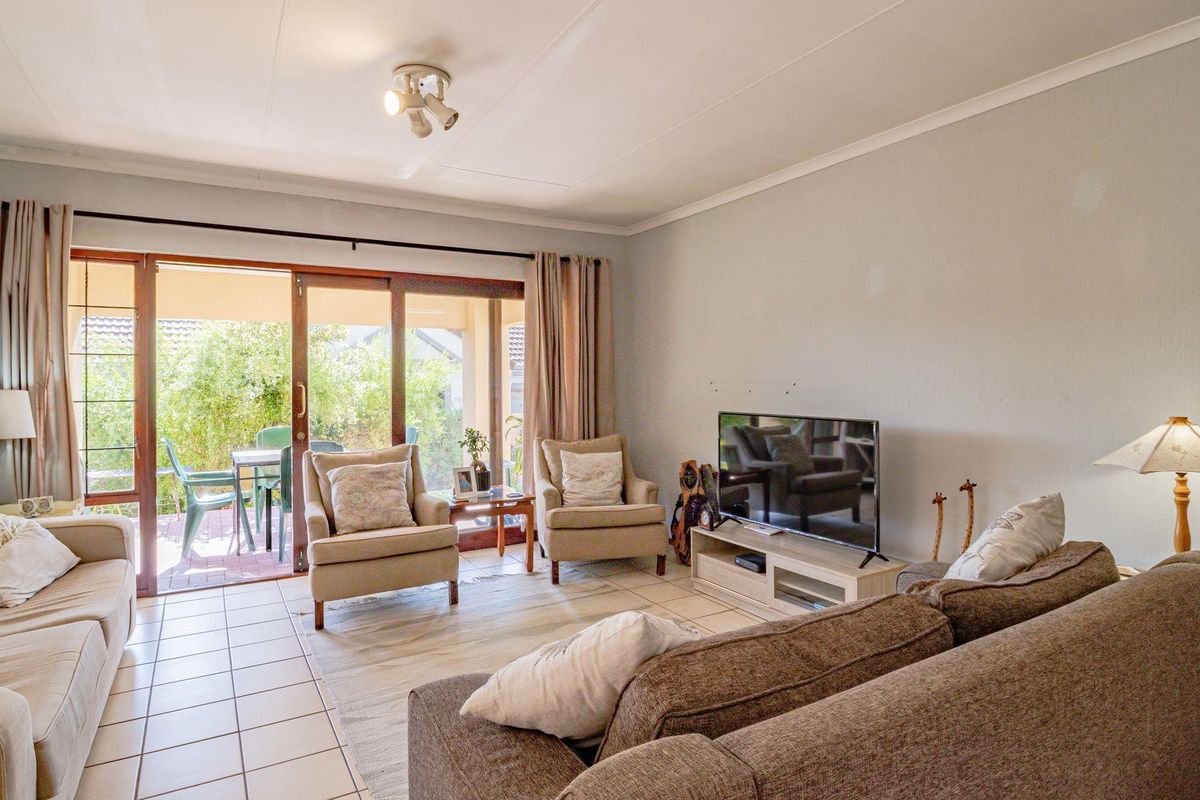A comfortable living room featuring tiled flooring and large sliding glass doors that provide direct access to an outdoor patio area.