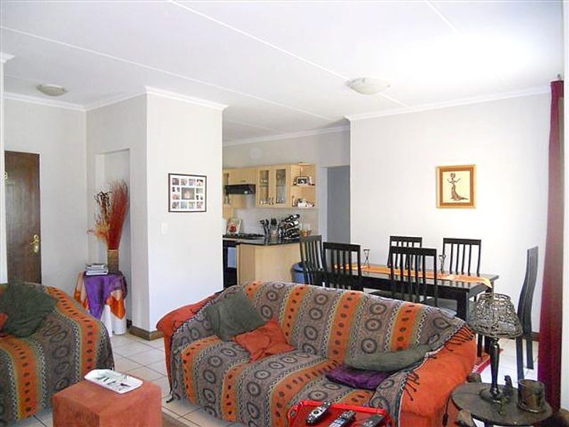 Open-plan living and dining area featuring tiled floors and a connected kitchen with built-in cabinetry and an extractor fan.