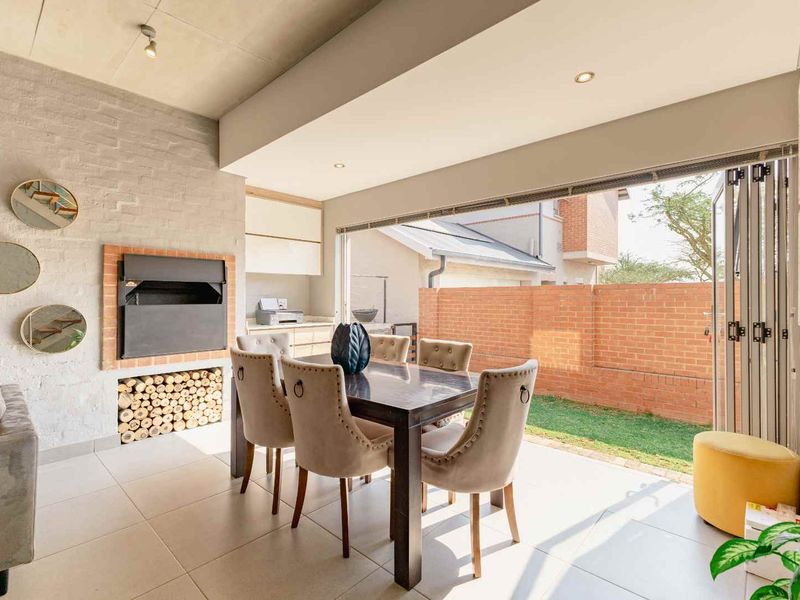 Open-plan living area featuring a built-in fireplace, exposed concrete ceiling, and large bi-fold doors opening to a private garden patio.