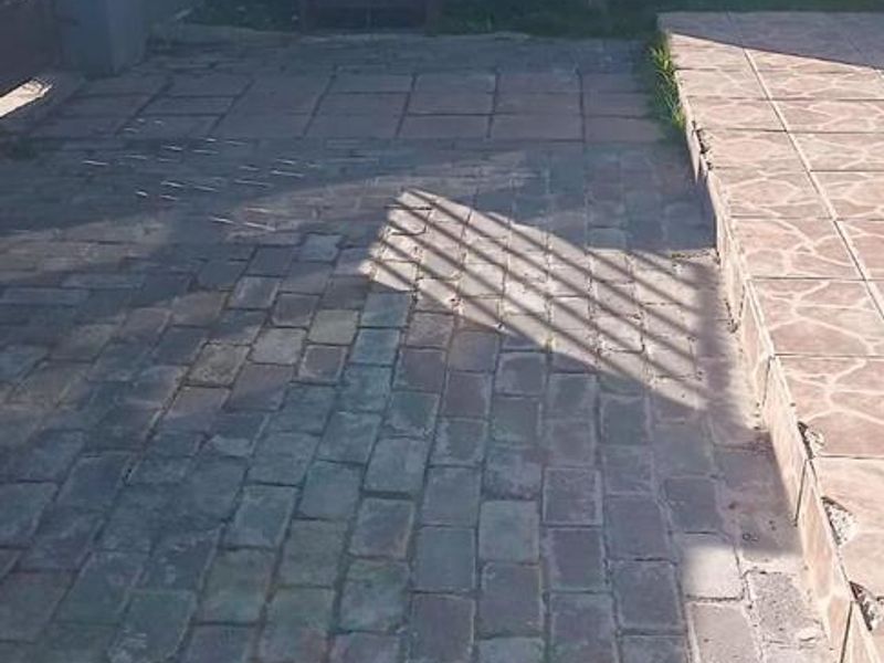 A rear outdoor area featuring brick paving and a precast concrete boundary wall, requiring maintenance and surface repairs.