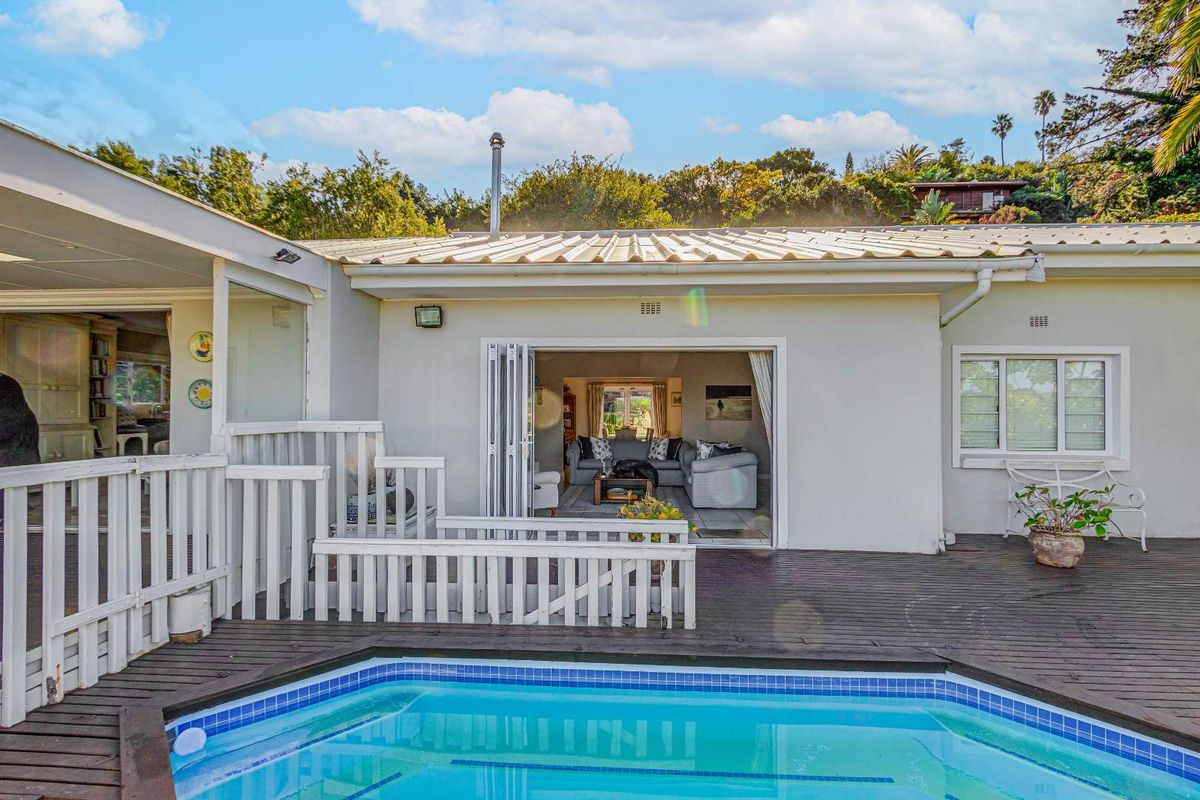 Rear exterior view featuring a swimming pool, timber deck, and bi-fold doors leading into the living area.