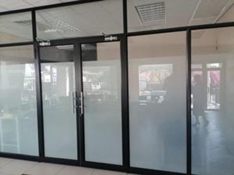 Modern office space featuring black aluminum framed glass partitioning with frosted privacy panels and double glass entry doors.