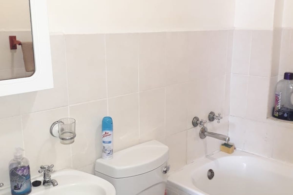 A functional bathroom featuring a pedestal basin, standard toilet, and bathtub with wall-mounted medicine cabinet and neutral ceramic tiling.