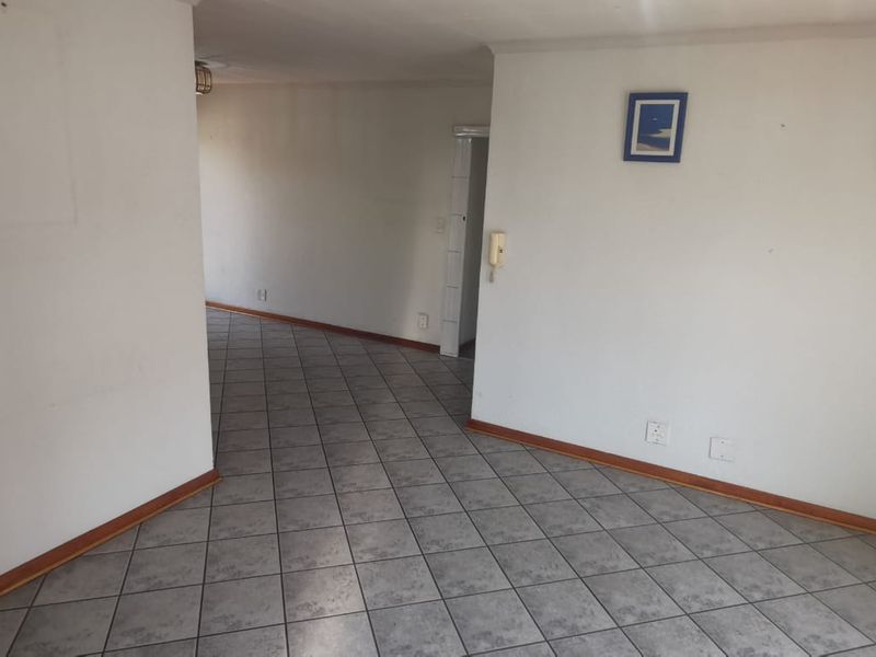 An empty living area featuring neutral tiled flooring and an integrated intercom system, offering a blank canvas for interior design.