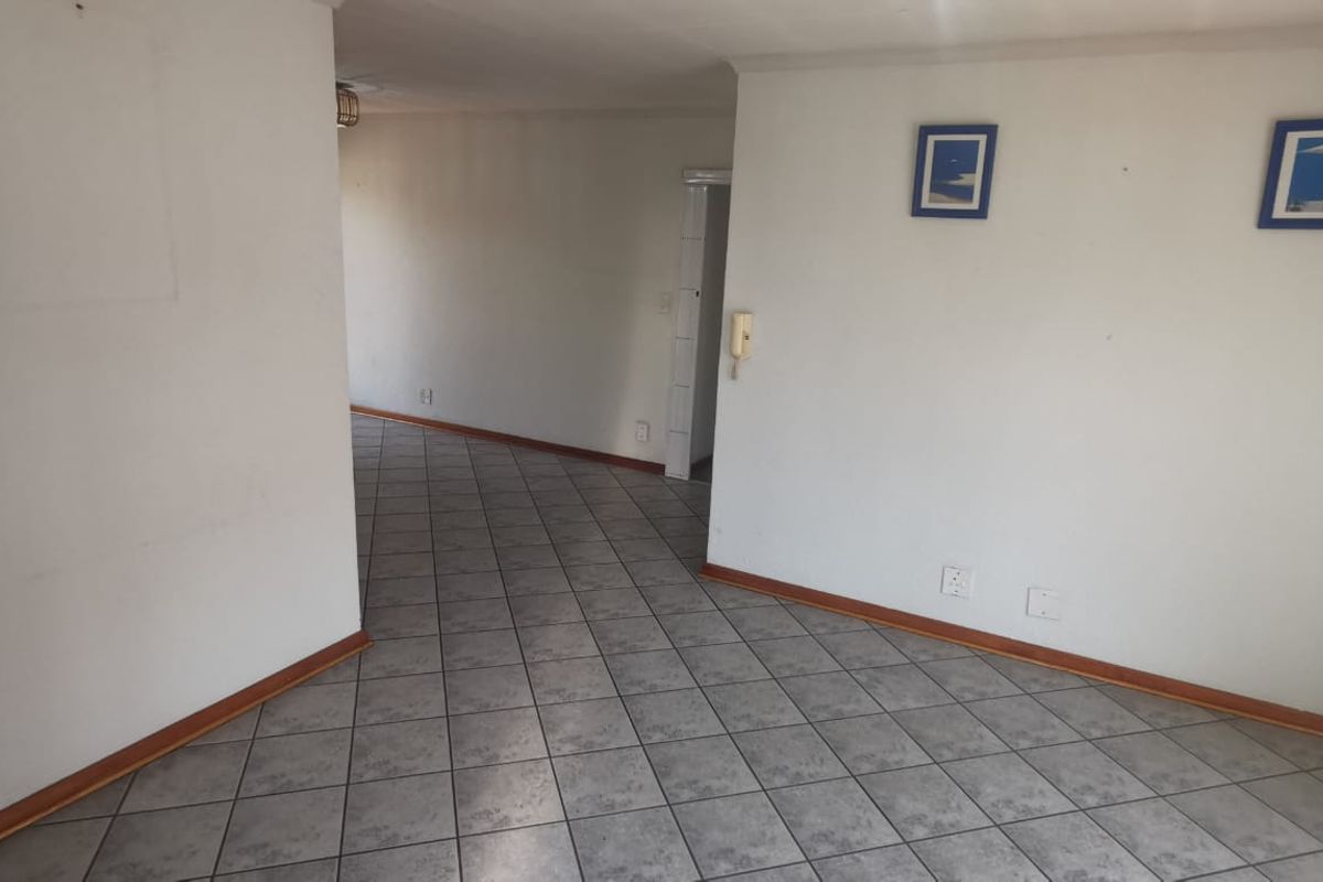 An empty living area featuring neutral tiled flooring and an integrated intercom system, offering a blank canvas for interior design.