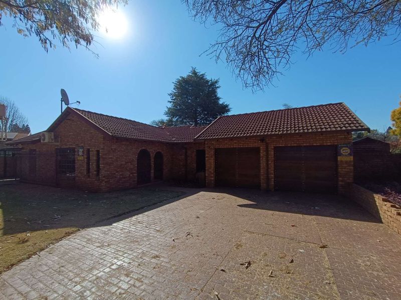 Front view of a face-brick house featuring a double garage, tiled roof, and a paved driveway.