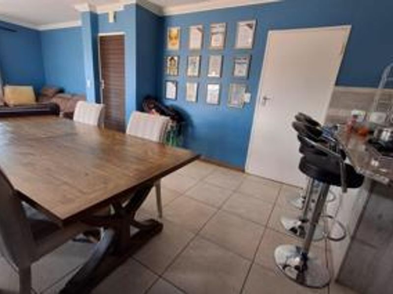 Open plan living and dining area featuring tiled flooring, a kitchen breakfast bar, and direct access to adjacent living spaces.