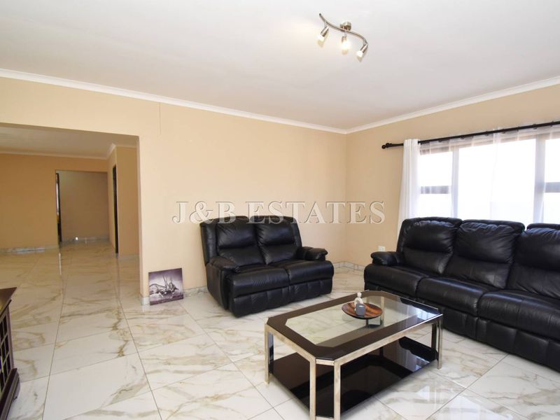 Spacious living room featuring polished marble-look floor tiles, neutral wall tones, and modern track lighting, providing a bright and open atmosphere.