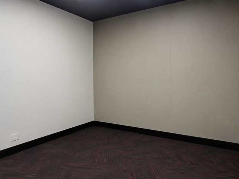 A clean, empty office space featuring modern herringbone carpet tiles, neutral wall finishes, and dark skirting boards, ready for professional fit-out.