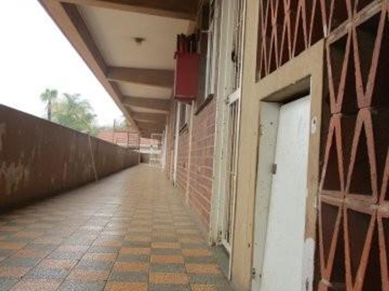An exterior balcony or walkway featuring tiled flooring, a decorative breeze block screen, and a security gate entrance.