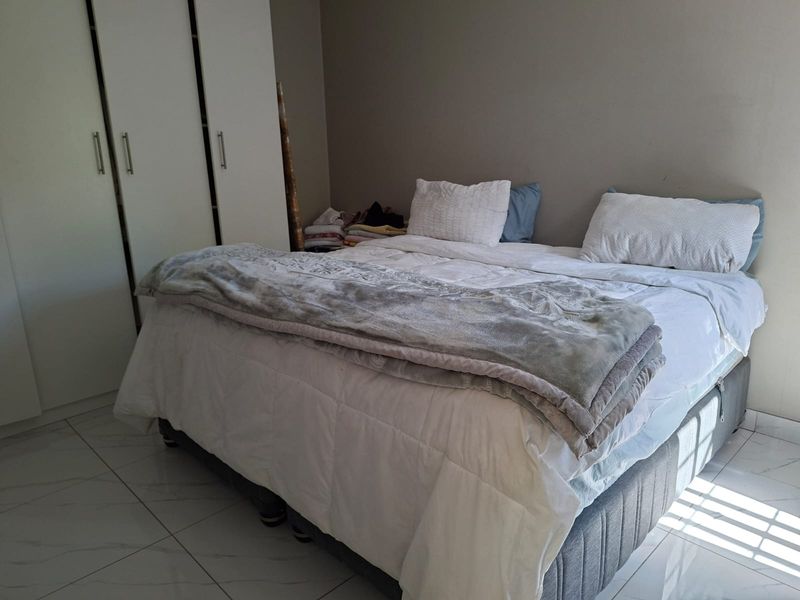 A bedroom featuring built-in cupboards and tiled flooring, providing a functional space with neutral wall finishes.