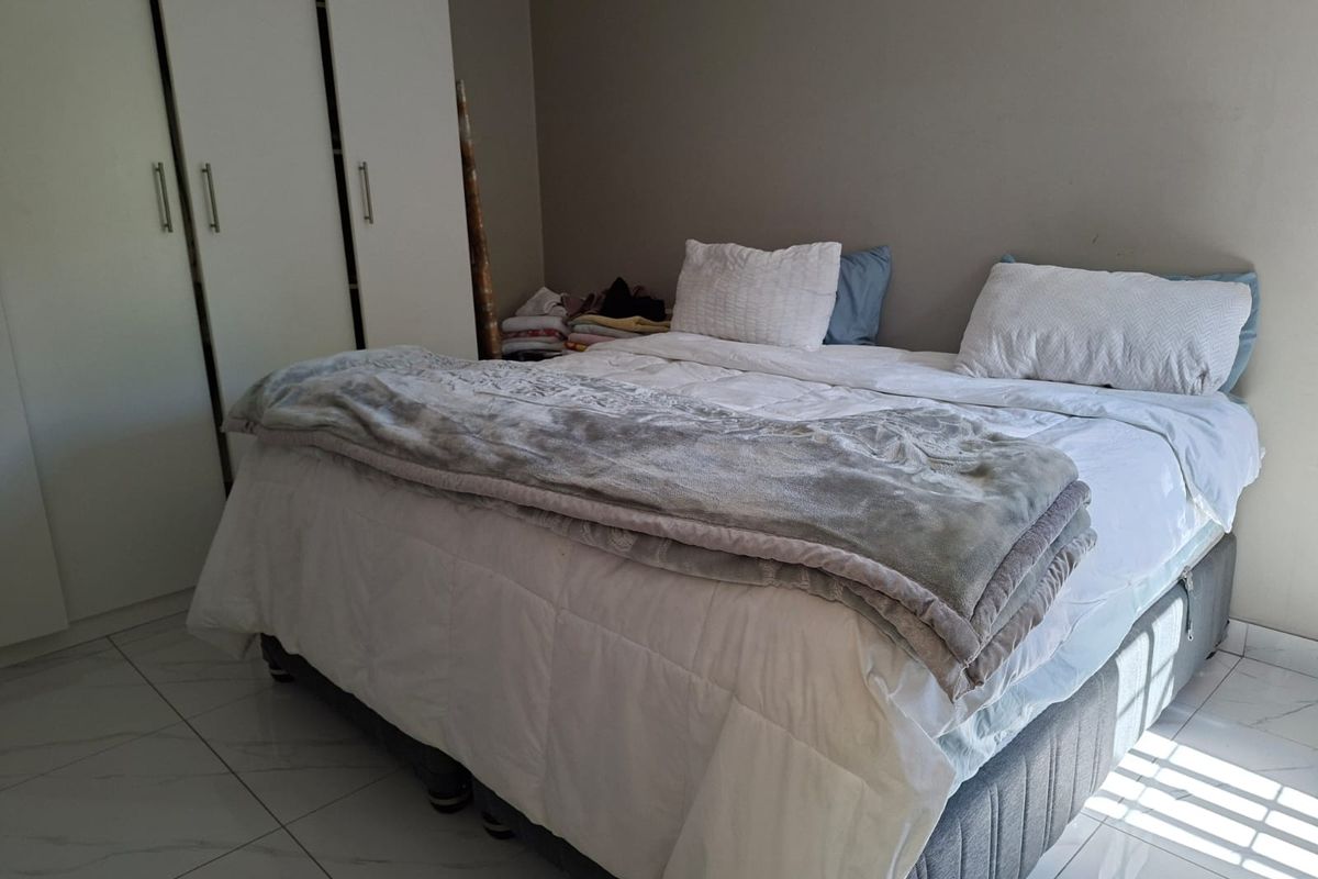 A bedroom featuring built-in cupboards and tiled flooring, providing a functional space with neutral wall finishes.