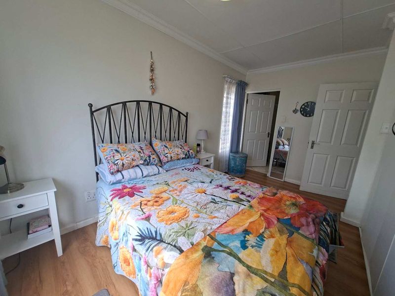 A functional bedroom featuring laminate flooring, coved ceilings, and standard panel doors, offering a neutral base for interior design updates.