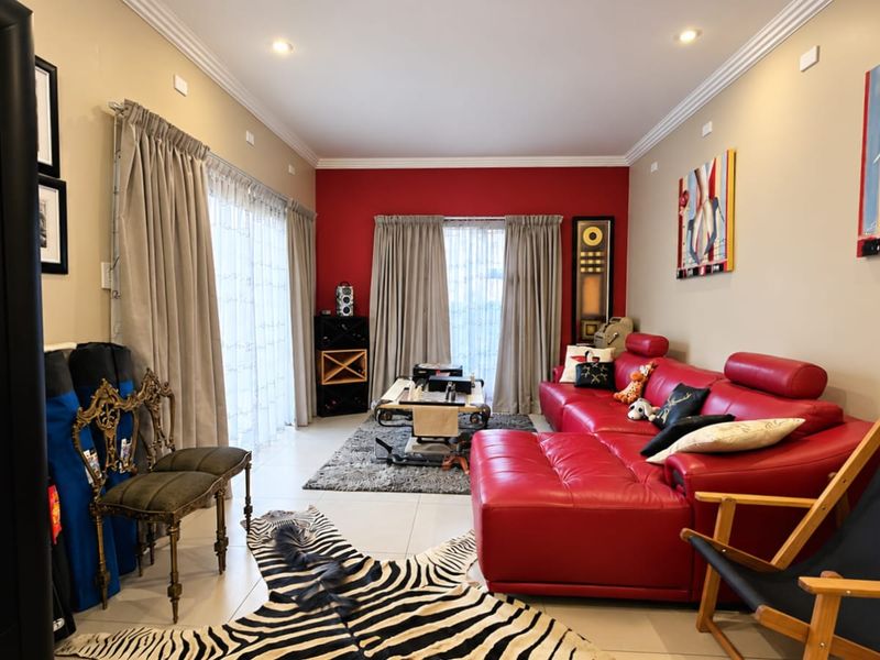 Spacious living room featuring tiled flooring, recessed downlighting, crown molding, and dual sliding glass doors providing access to the exterior.