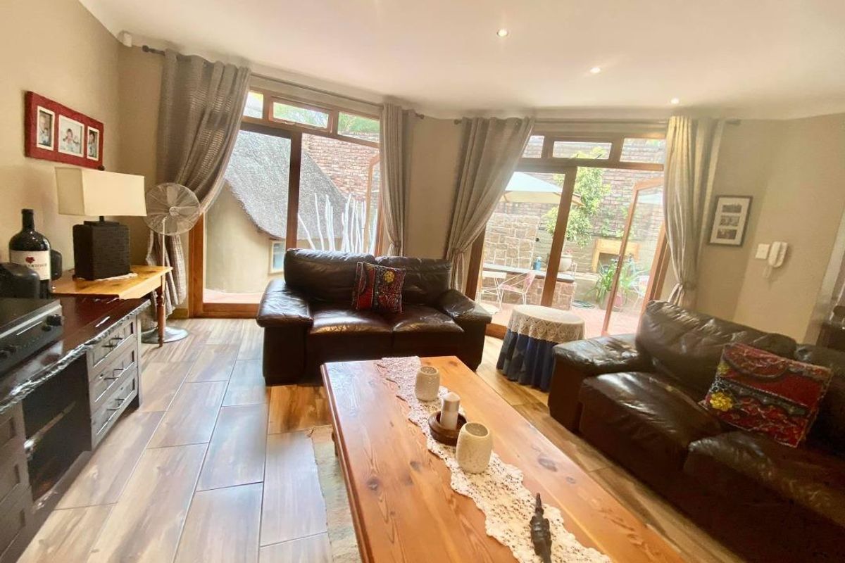A comfortable living room featuring wood-look tile flooring, recessed ceiling lighting, and large glass doors providing direct access to the rear patio area.
