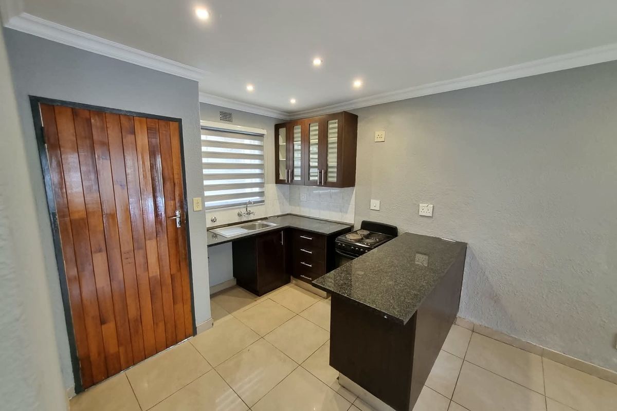 A clean, functional kitchen featuring dark wood cabinetry, granite countertops, tiled flooring, and a breakfast nook, offering a neutral and well-maintained space.