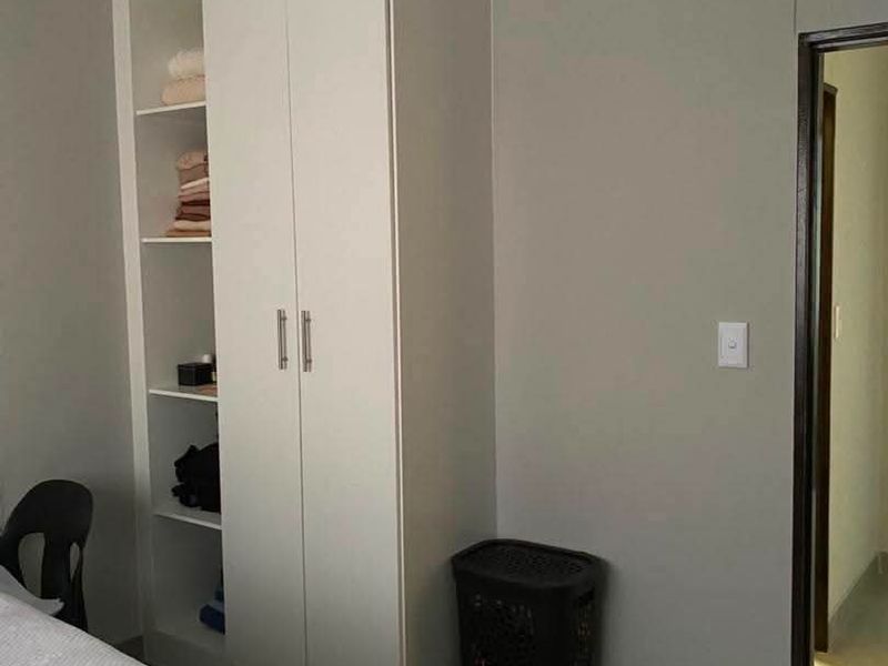A bedroom featuring a white built-in wardrobe with integrated shelving and neutral wall finishes.