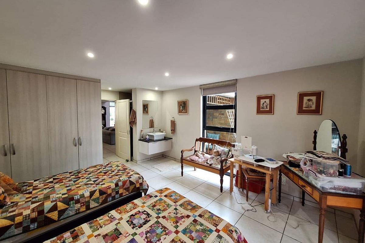 Spacious bedroom featuring built-in wardrobes, tiled flooring, recessed lighting, and an integrated vanity basin area.