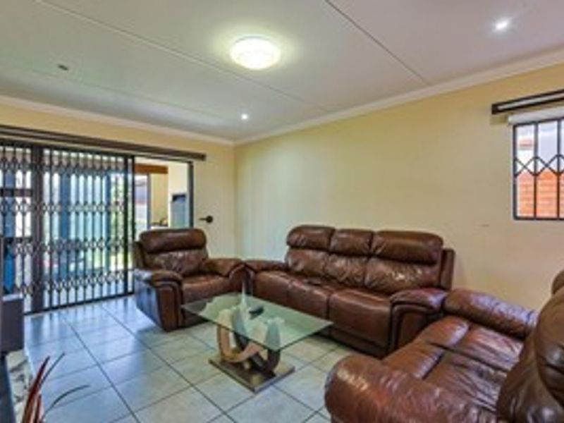A living room featuring tiled flooring, recessed lighting, and a sliding glass door with a security gate leading to the exterior.