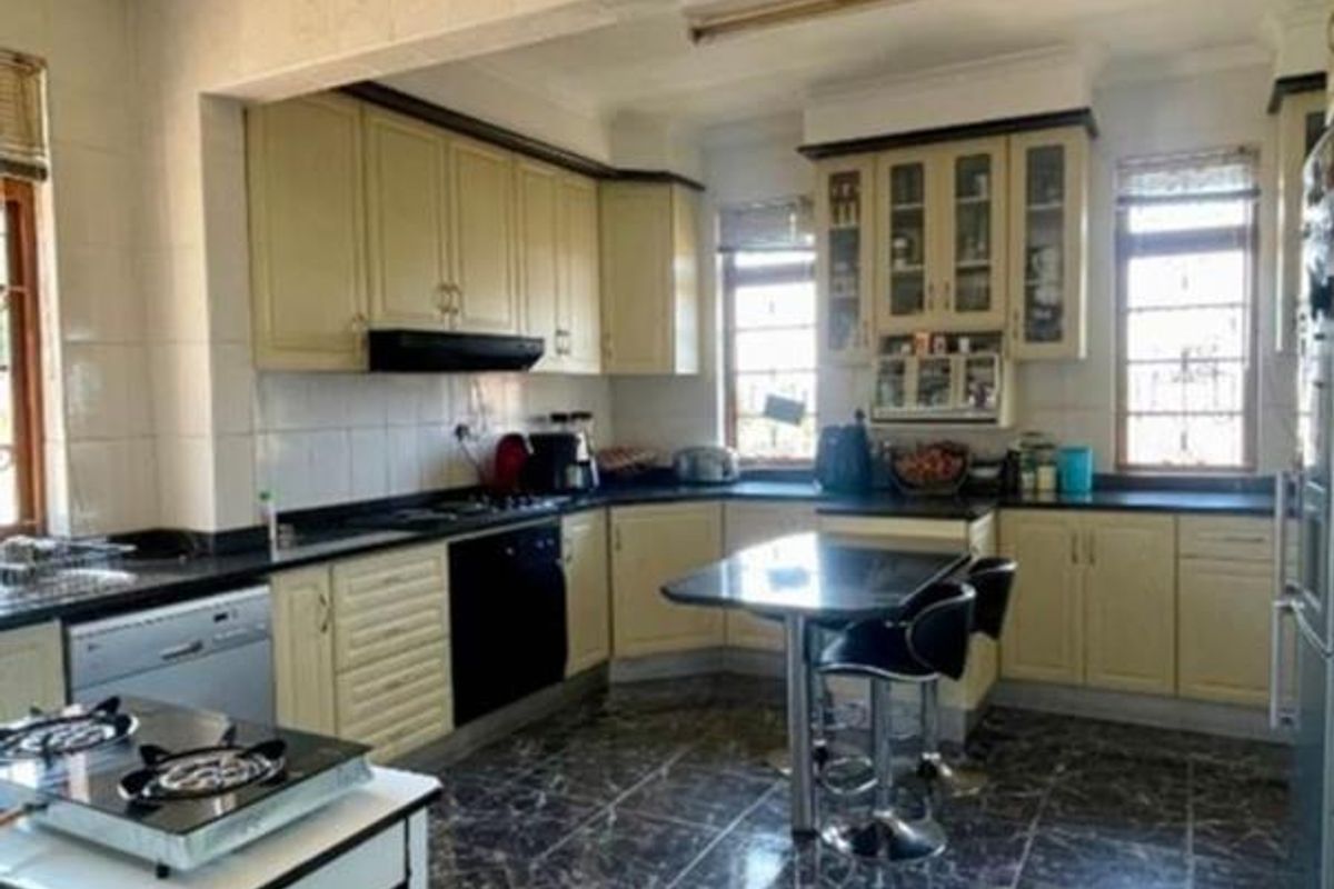 A functional kitchen featuring cream-colored cabinetry, dark countertops, and dark marble-effect floor tiles with integrated cooking appliances.