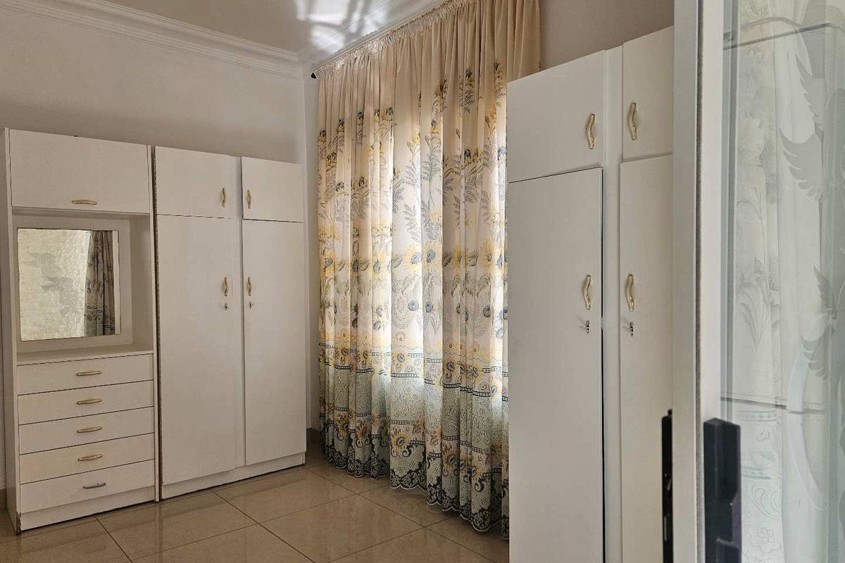 Bedroom featuring tiled flooring and extensive built-in cupboard storage with integrated vanity unit.