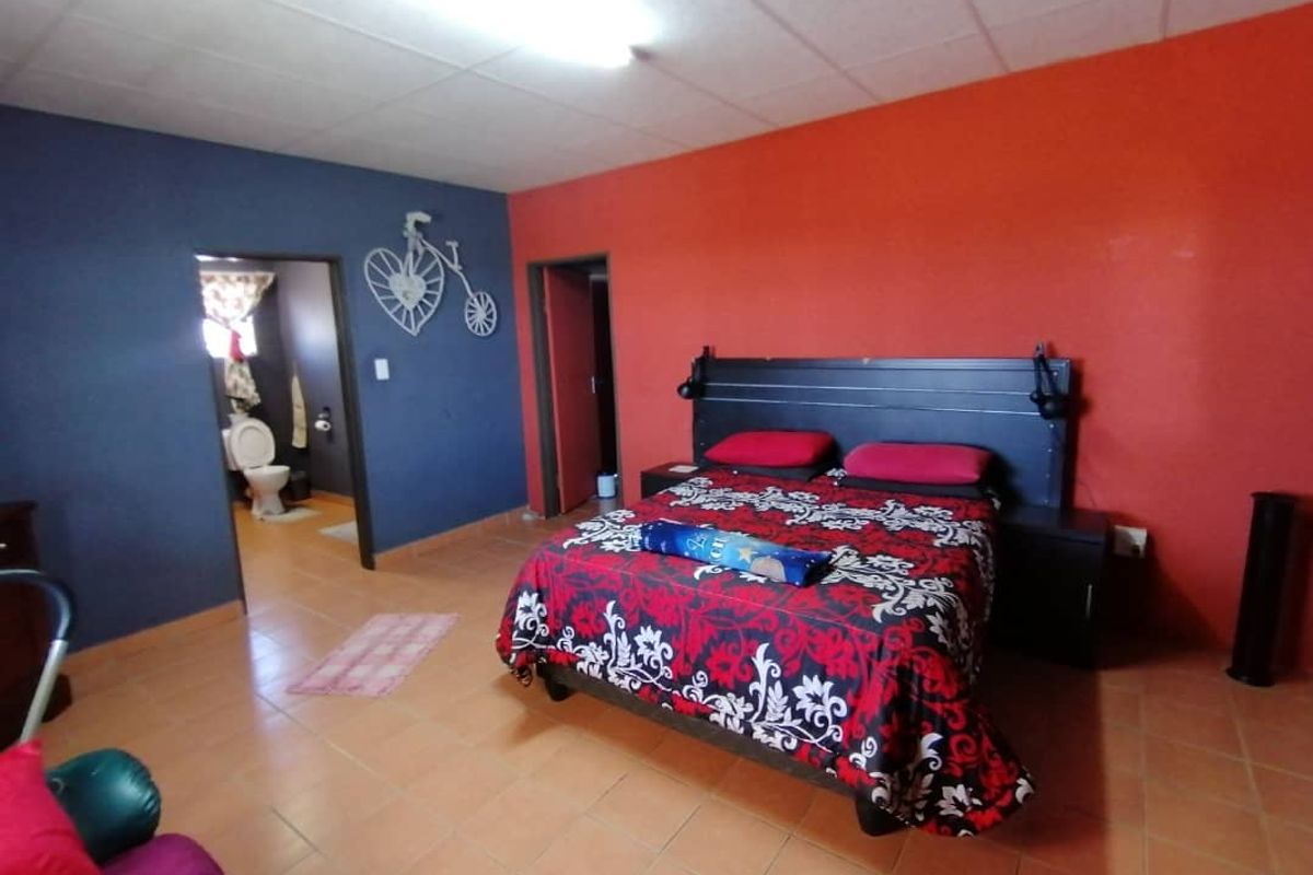 A bedroom featuring tiled flooring and contrasting painted walls, with an adjoining bathroom visible through the doorway.