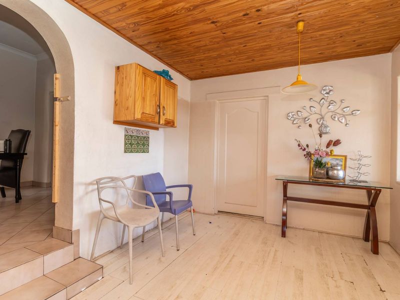 Living area featuring a timber ceiling, arched entryway, and tiled steps leading to an adjacent room, with potential for cosmetic updates.
