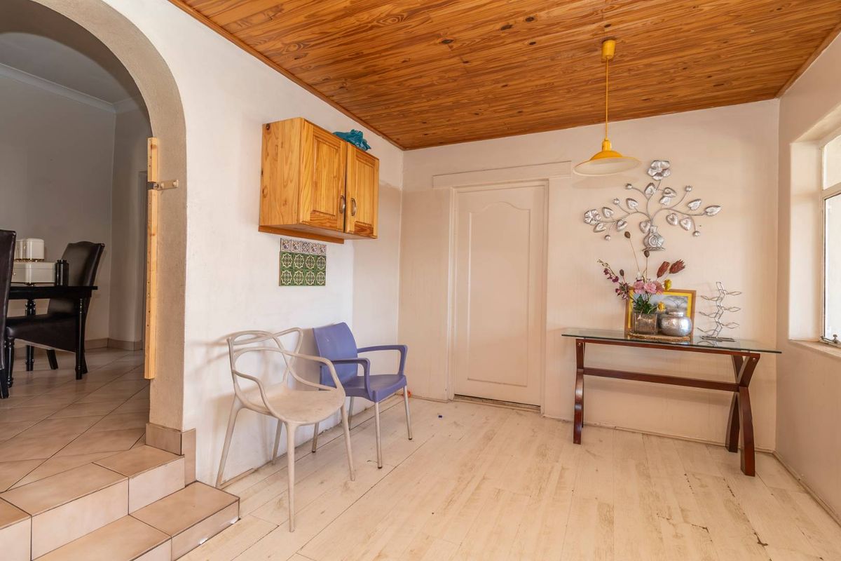 Living area featuring a timber ceiling, arched entryway, and tiled steps leading to an adjacent room, with potential for cosmetic updates.