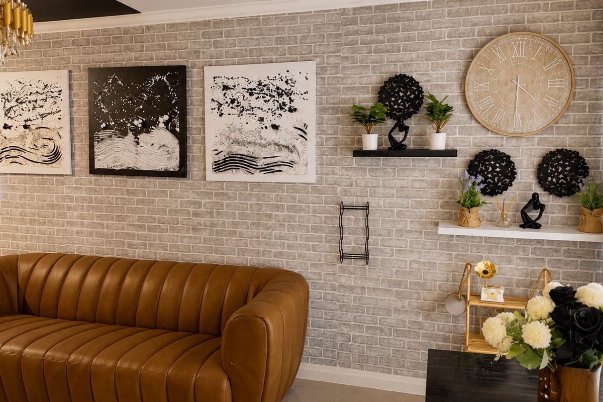 A well-maintained living room featuring a textured brick-effect feature wall, floating display shelves, and modern recessed ceiling lighting.