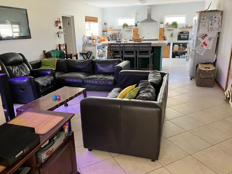 Open-plan living and kitchen area featuring tiled flooring, a central kitchen island with breakfast bar seating, and an integrated extractor fan.