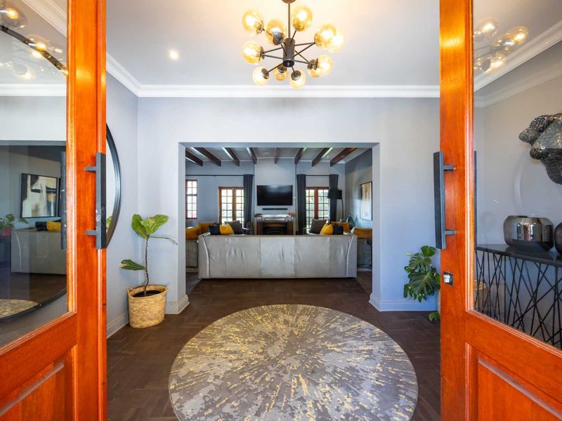 Welcoming entrance foyer featuring elegant herringbone flooring, crown molding, and a statement chandelier, leading directly into the main living area.