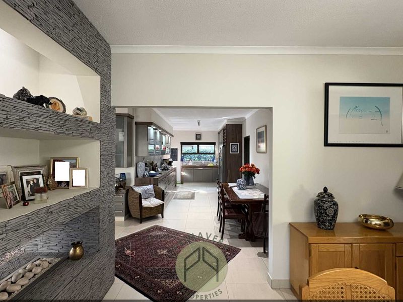 Open plan living and dining area featuring a textured stone feature wall, tiled flooring, and a seamless transition into the kitchen space.