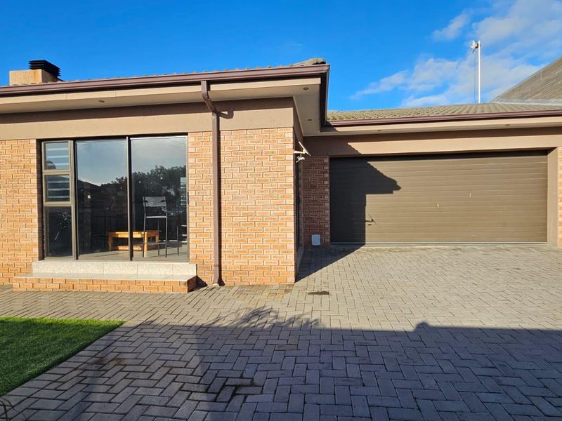 Front view of a modern brick house featuring a paved driveway, a single garage with a sectional door, and a sliding glass door entrance.