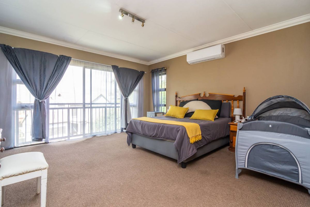 Spacious bedroom featuring large sliding glass doors, wall-mounted air conditioning unit, and neutral wall finishes.