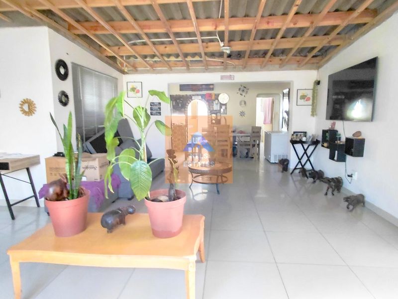Open-plan living area featuring tiled flooring and an exposed timber ceiling structure, offering a versatile space for renovation and interior design updates.