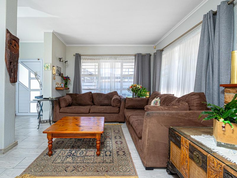 A comfortable living room featuring tiled flooring, a stone fireplace, and large windows that provide ample natural light.