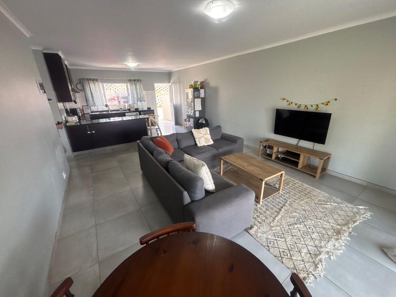 An open-plan living and kitchen area featuring tiled flooring, dark cabinetry, and a functional layout suitable for modern living.