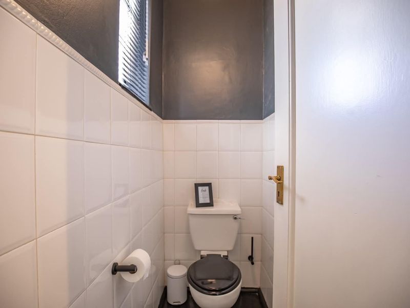 A compact bathroom featuring white wall tiles, a dark painted upper wall section, and a standard toilet.