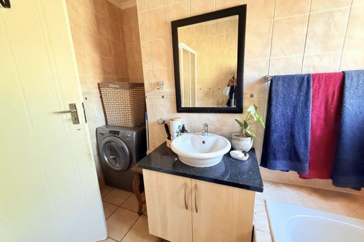 A bathroom featuring a vanity with a vessel sink, tiled walls, and a built-in space for a washing machine.