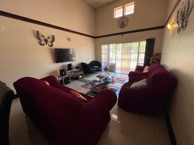 Spacious living room featuring high ceilings, tiled flooring, and large sliding glass doors with security gates leading to the exterior.