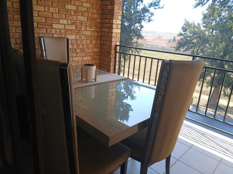 A covered balcony featuring exposed brick walls, tiled flooring, and a metal balustrade, offering an outdoor space with views.