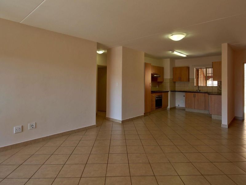 Spacious open-plan living area featuring tiled flooring and a functional kitchen with built-in cabinetry, oven, and extractor fan.