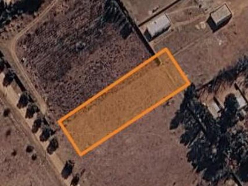 An aerial view of a vacant residential plot with an orange boundary overlay indicating the property lines.