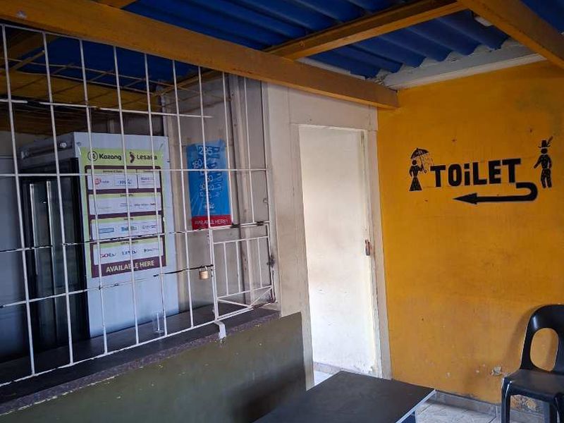 A utility or service area featuring a corrugated metal roof, security grille, and tiled flooring, currently used as a service point.