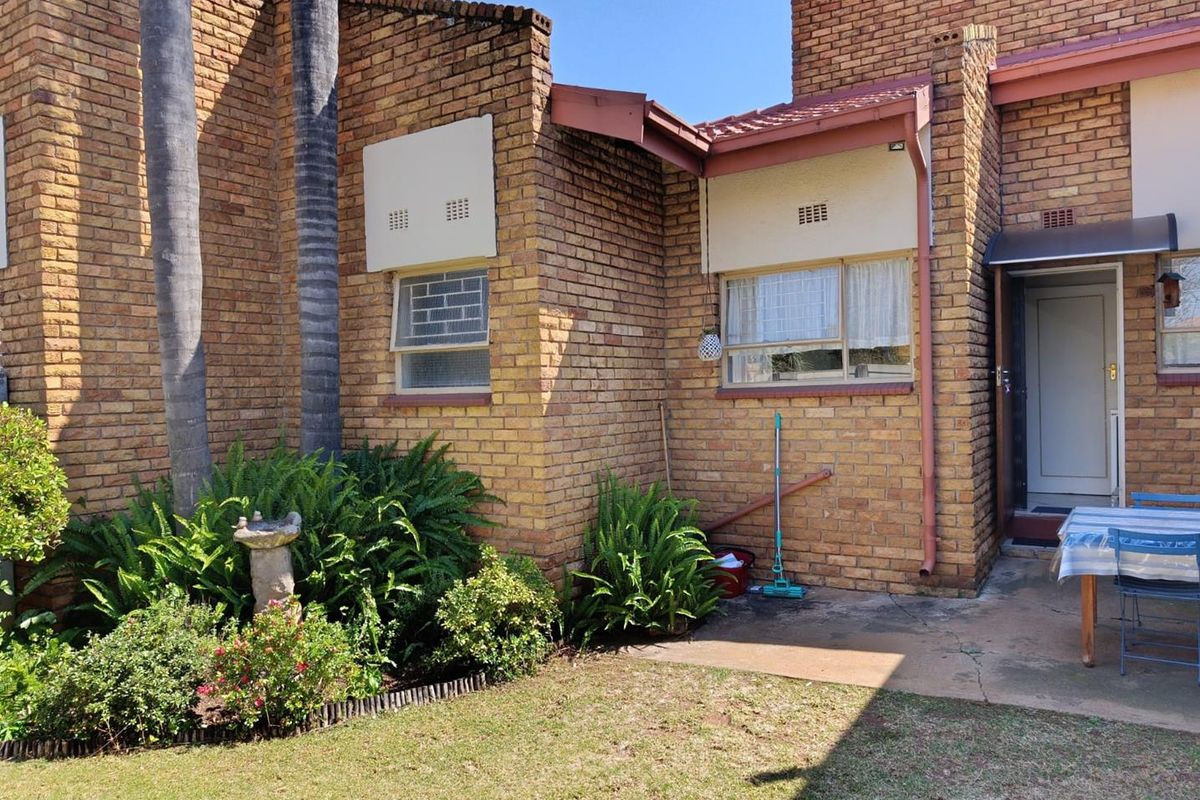 Rear exterior view of the cottage featuring face brick walls, a tiled roof, and a small concrete patio area adjacent to the garden.