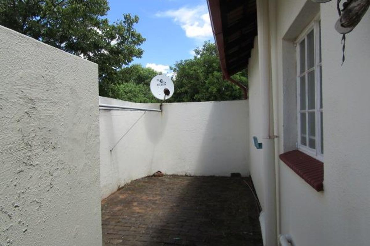 A private, paved rear courtyard area featuring high boundary walls, a satellite dish, and direct access to the side of the residence.